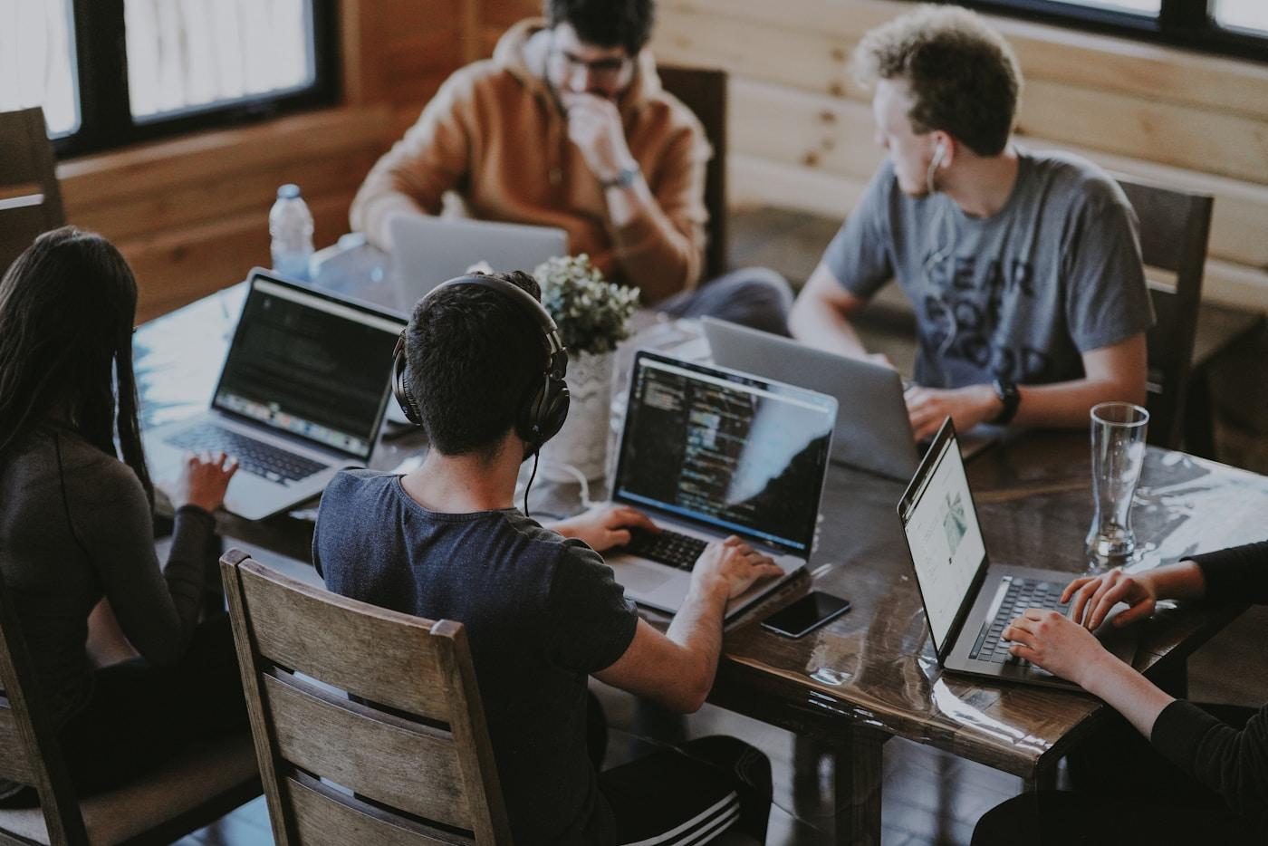 Equipa multicultural à volta de um portátil, a colaborar em solução digital